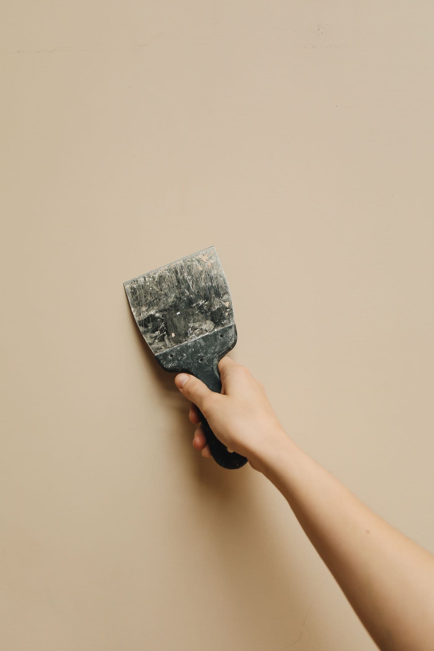 Putty knife applying compound during a drywall patch